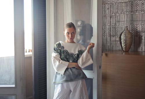 Photo of a Woman Standing by a Glass Door