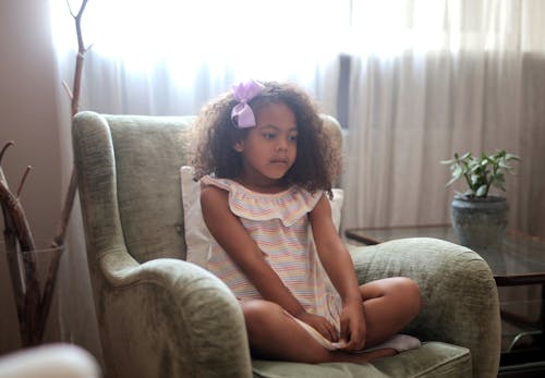 Little Girl Sitting in Armchair Thinking