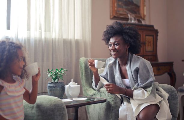 A joyful mother and daughter share a tea moment in their cozy living room