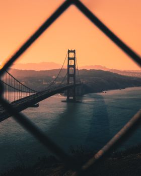 日落时分，金门大桥的壮丽景色被栅栏框住，在水面上投下戏剧性的阴影