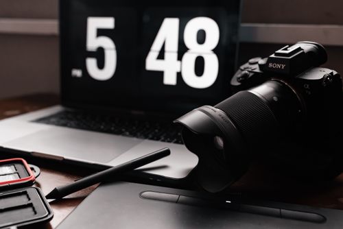 Free A stylish setup featuring a camera, laptop, and digital pen on a desk. Stock Photo