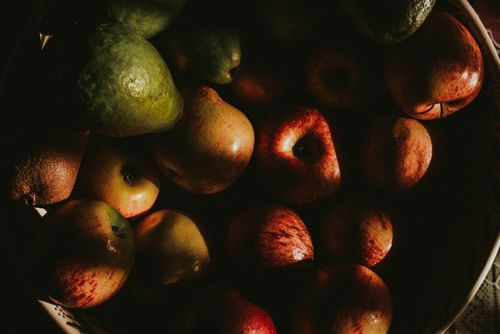 Free From above of heap of ripe shiny apples and avocados arranged in big bowl and placed on table Stock Photo