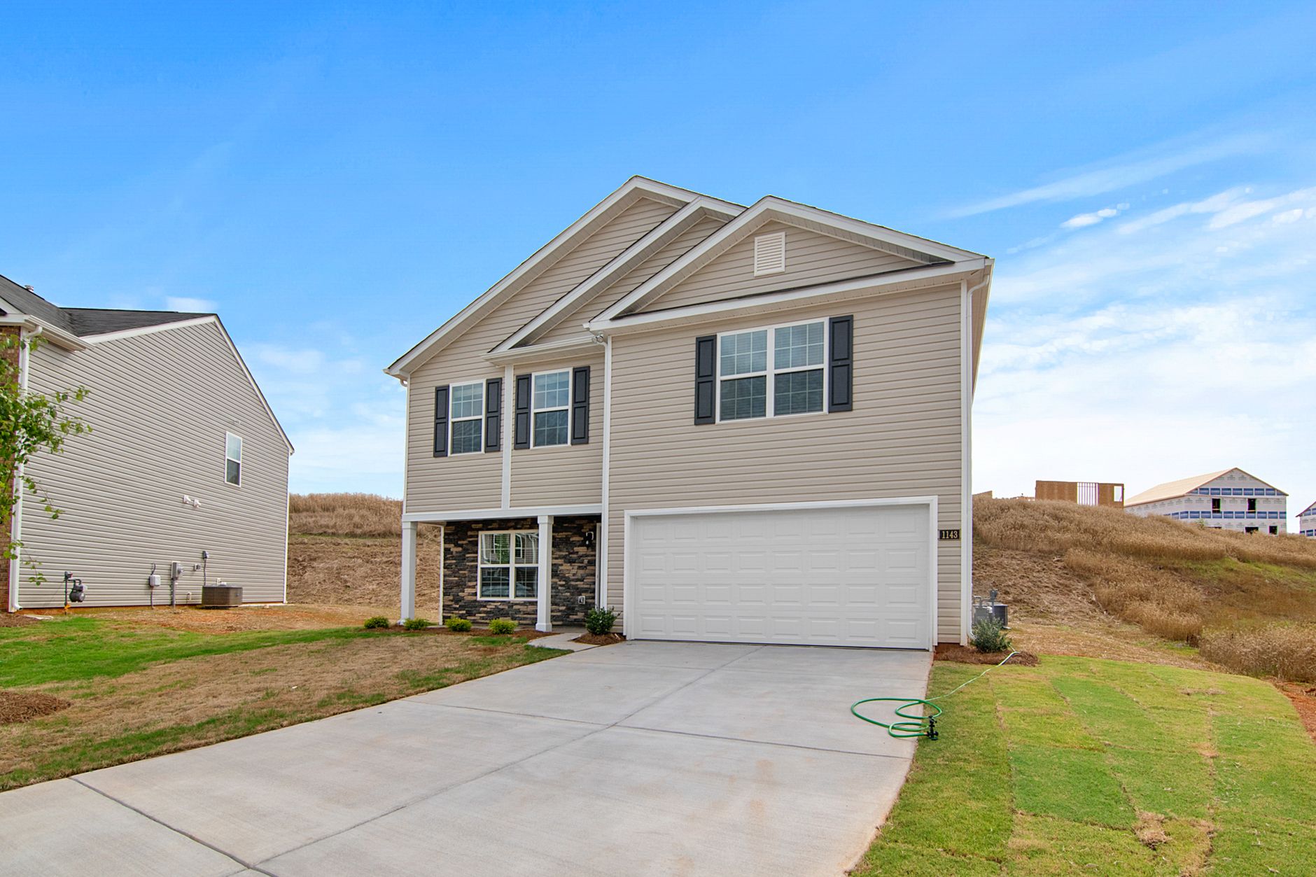 A modern suburban home with a spacious driveway and two-car garage in a clear sky setting.