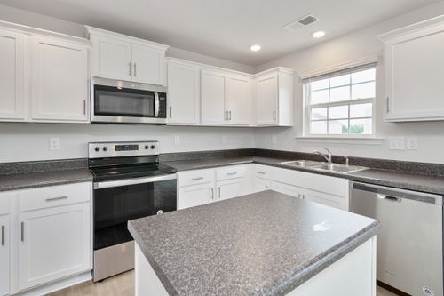 Free Bright white kitchen featuring stainless steel appliances and sleek countertops. Stock Photo