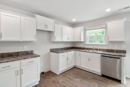 Free Spacious white kitchen featuring stainless steel appliances, white cabinets, and wood flooring. Stock Photo