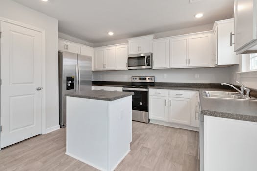 Bright modern kitchen featuring white cabinets and stainless steel appliances. Ideal for interior design and real estate.