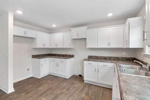 Free Spacious modern kitchen featuring white cabinetry, wooden floors, and natural lighting. Ideal for contemporary homes. Stock Photo