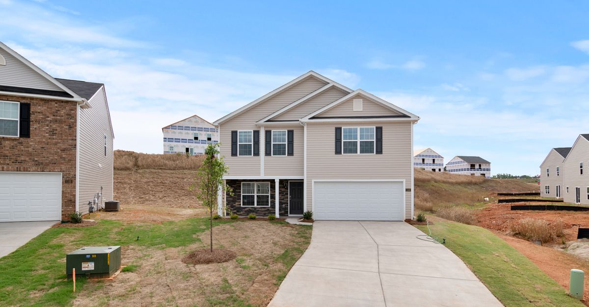 Newly constructed suburban home with spacious driveway and developing neighborhood.