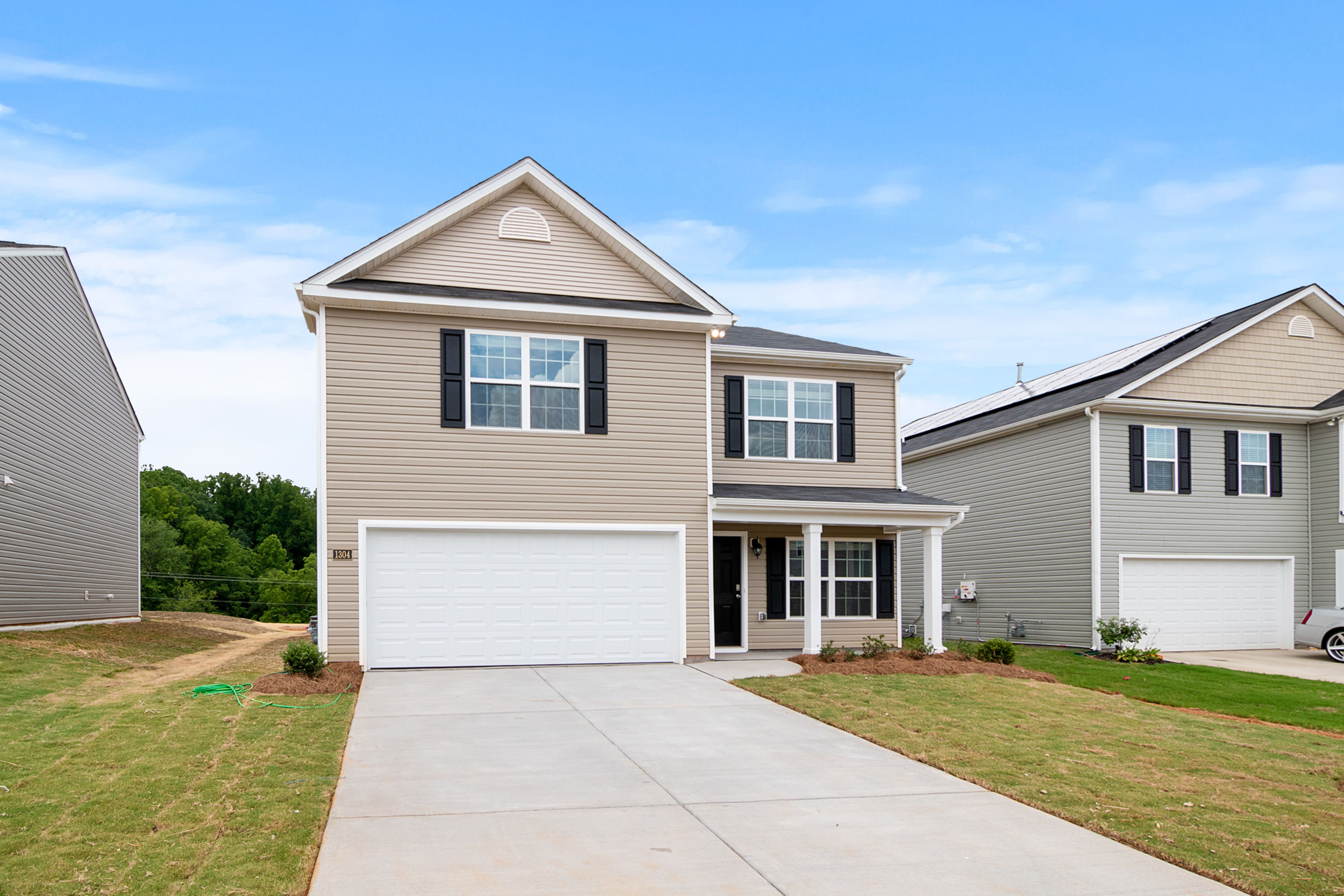 Alt Text: A beautifully designed two-story white and gray contemporary residential house under a clear blue sky, showing clean architectural lines.