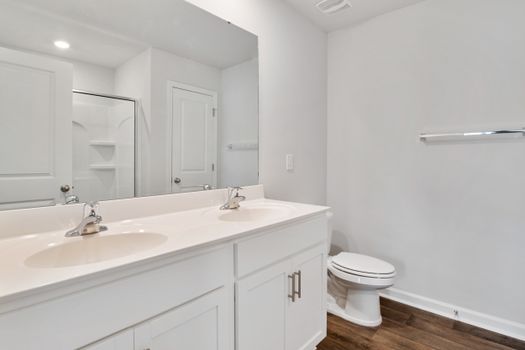 Bright modern bathroom interior featuring double sinks, mirror, and shower.