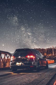 A parked car under a starry sky on a wooden bridge at night, evoking a sense of wanderlust and adventure.