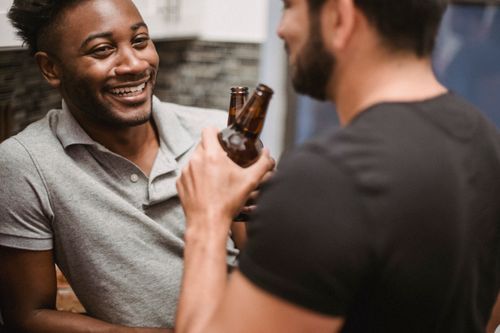 Free Joyful couple toasting with beer bottles indoors. Capturing love and happiness. Stock Photo