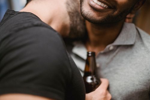 Free A close-up of a smiling couple embracing warmly indoors with a beer bottle. Stock Photo