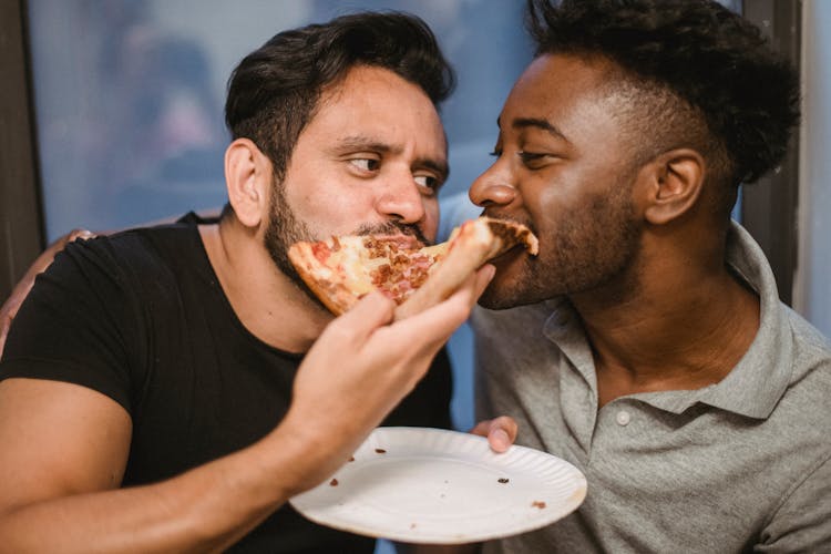 Two Men Eating A Pizza Together