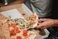 Person Holding Pizza With Green Leaves