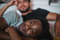 Man in Gray and Black Stripe Shirt Lying on Bed