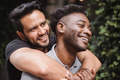 Photo of a Man Hugging Another Man while Smiling