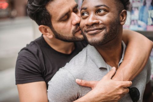 Free A loving gay couple embraces and kisses in an urban setting, highlighting romance and diversity. Stock Photo