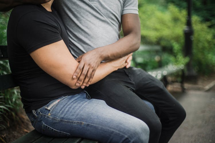 A Person In Gray Shirt Sitting On The Lap Of The Person Wearing Black Shirt