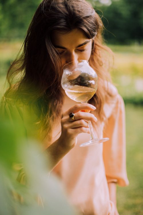 Free Woman enjoying a peaceful moment with a glass of white wine outdoors. Stock Photo