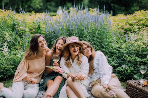 Happy Women Sitting Next tp Each Other Near Green Plants