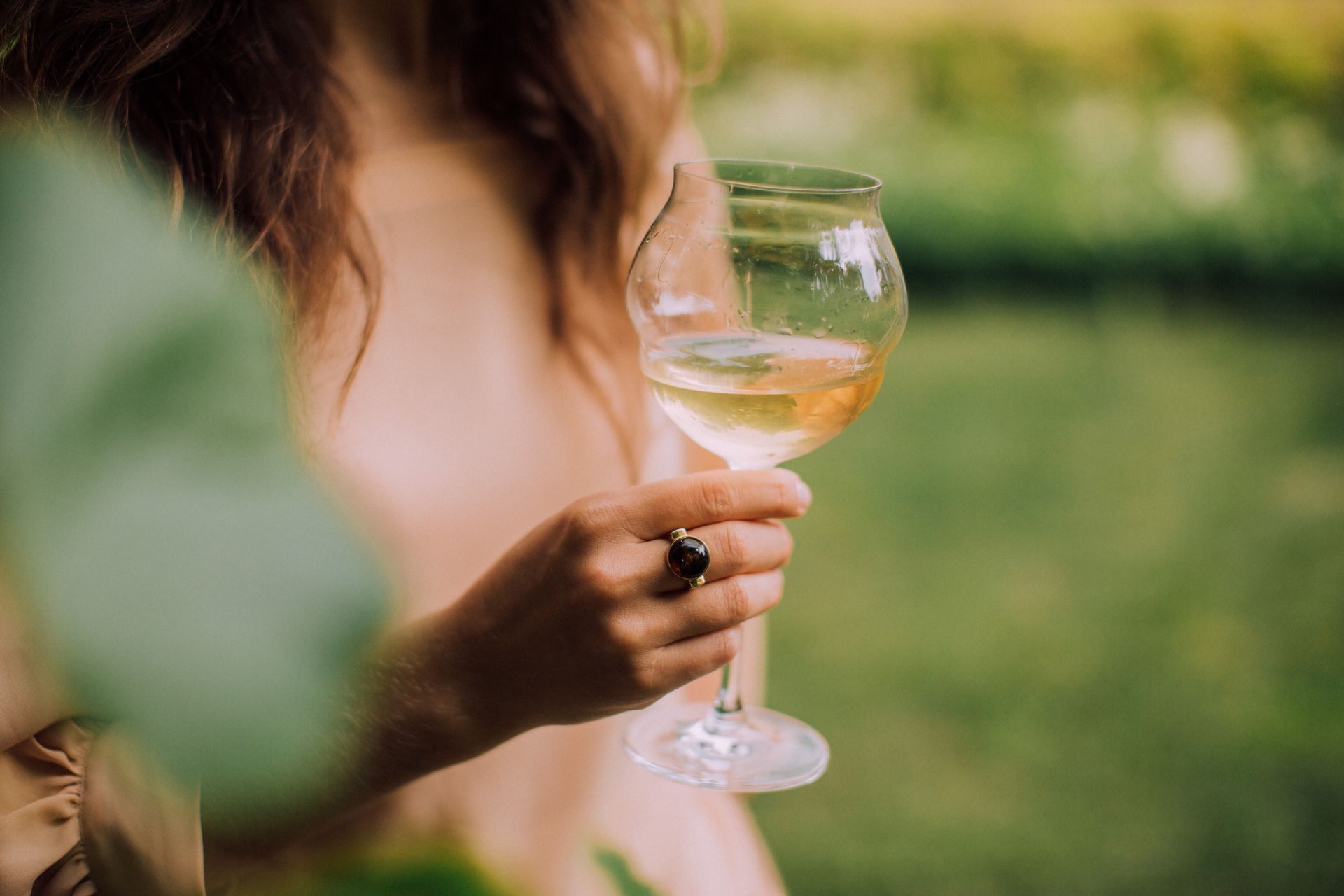 A Hand Wearing Ring Holding a Glass of White Wine
