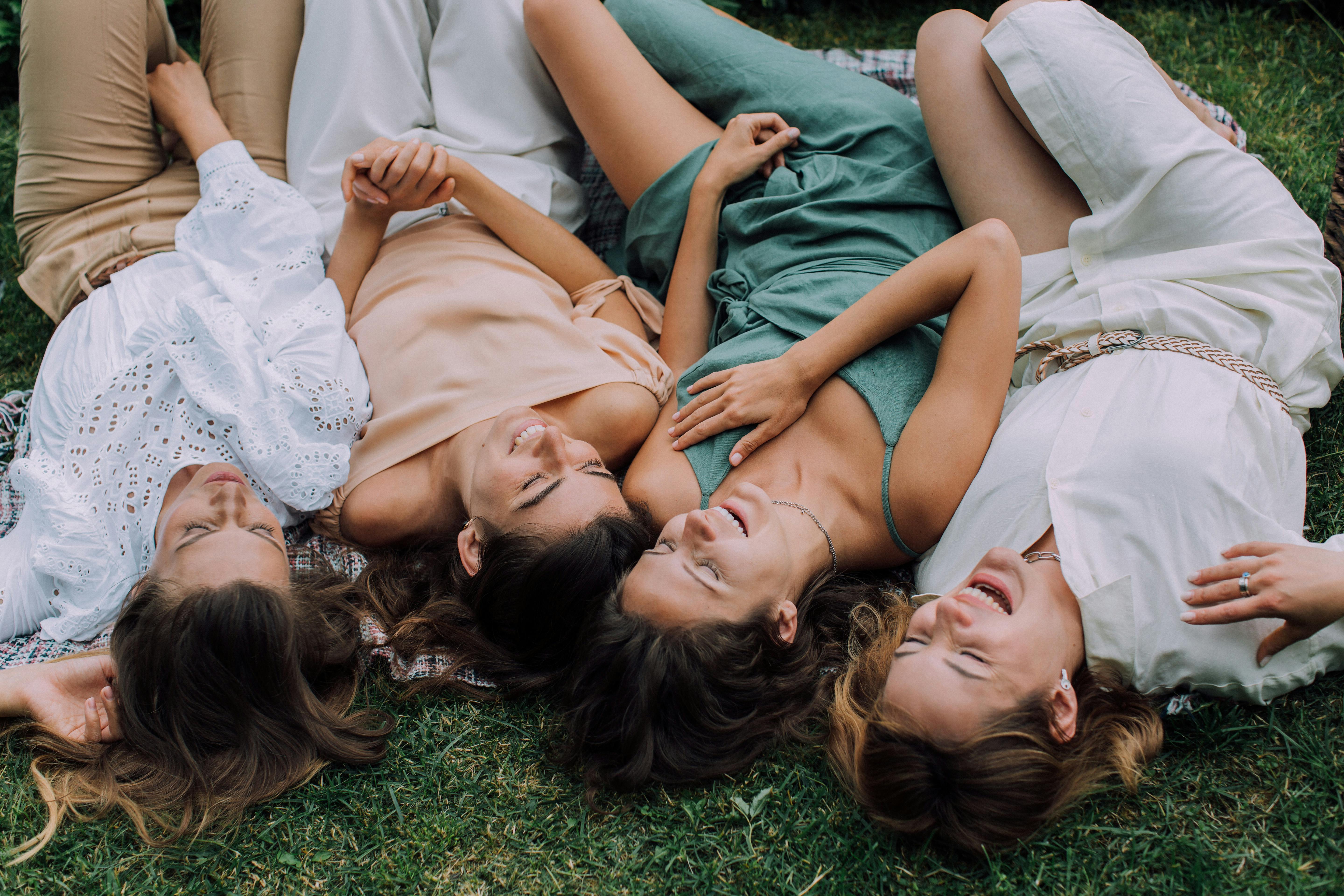 overhead shot of women lying on the grass while laughing