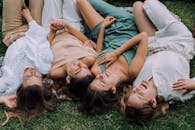 四个女人躺在草地上开怀大笑，体现了友谊和欢乐