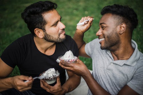 Men Sitting Close Next to Each Other while Eating Ice Cream