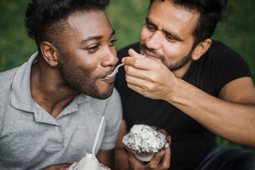 Men Sitting Close Next to Each Other while Eating Ice Cream