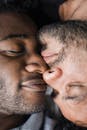 一张两个男人温柔拥抱的特写照片，他们安详地闭着眼睛