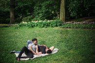 Woman in Black Tank Top and Black Pants Lying on White Textile on Green Grass Field