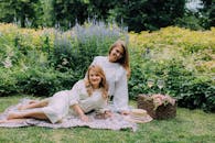 两位女士在生机盎然的花园里，享受着一场宁静的野餐，这正是完美生活与休闲方式的写照