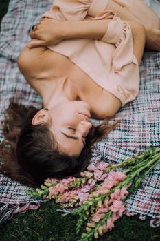 一个女人在户外铺着粉红色花朵的毯子上安静休息