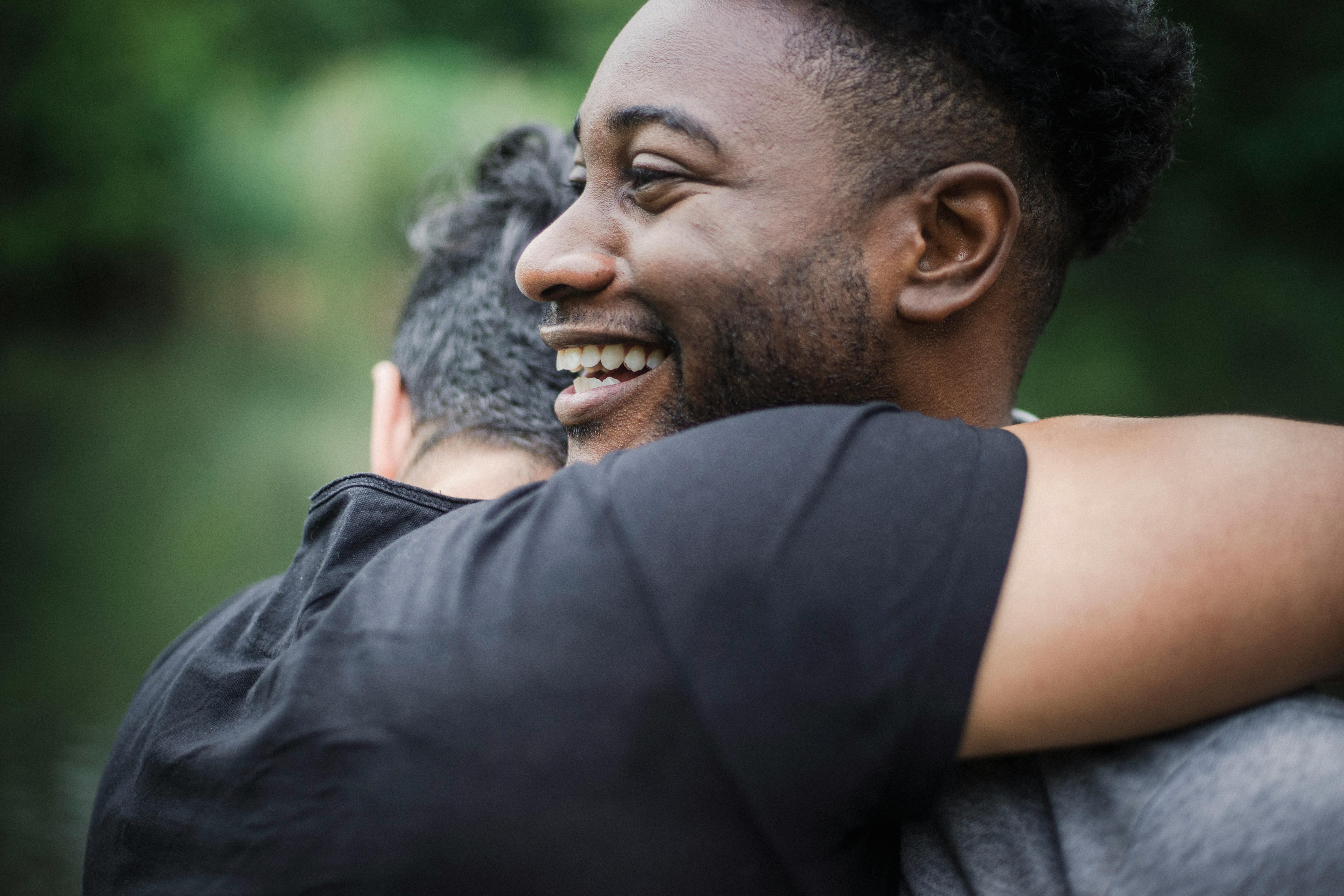 两个成年人在户外自然环境中快乐地拥抱，暗示着友谊或重逢