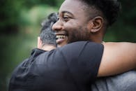 两个成年人在户外自然环境中快乐地拥抱，暗示着友谊或重逢