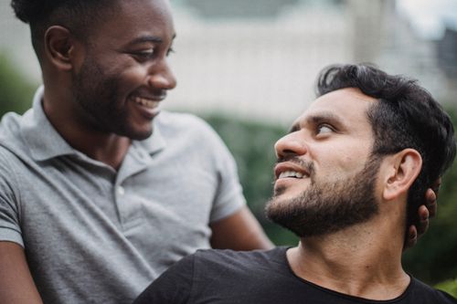Free Smiling couple enjoying a joyful moment in a green outdoor setting. Stock Photo