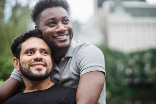 Free Cheerful couple enjoying a moment of affection in a sunny outdoor setting. Stock Photo