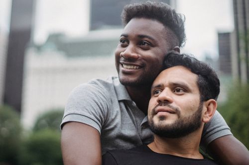 Free Happy couple embraces while smiling outdoors in a city setting. Stock Photo