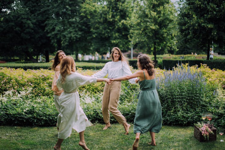 Group Of Friends Dancing Holding Hands In The Park