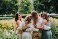 四个女人在绿色的公园里一起享受阳光明媚的一天，互相拥抱，微笑着