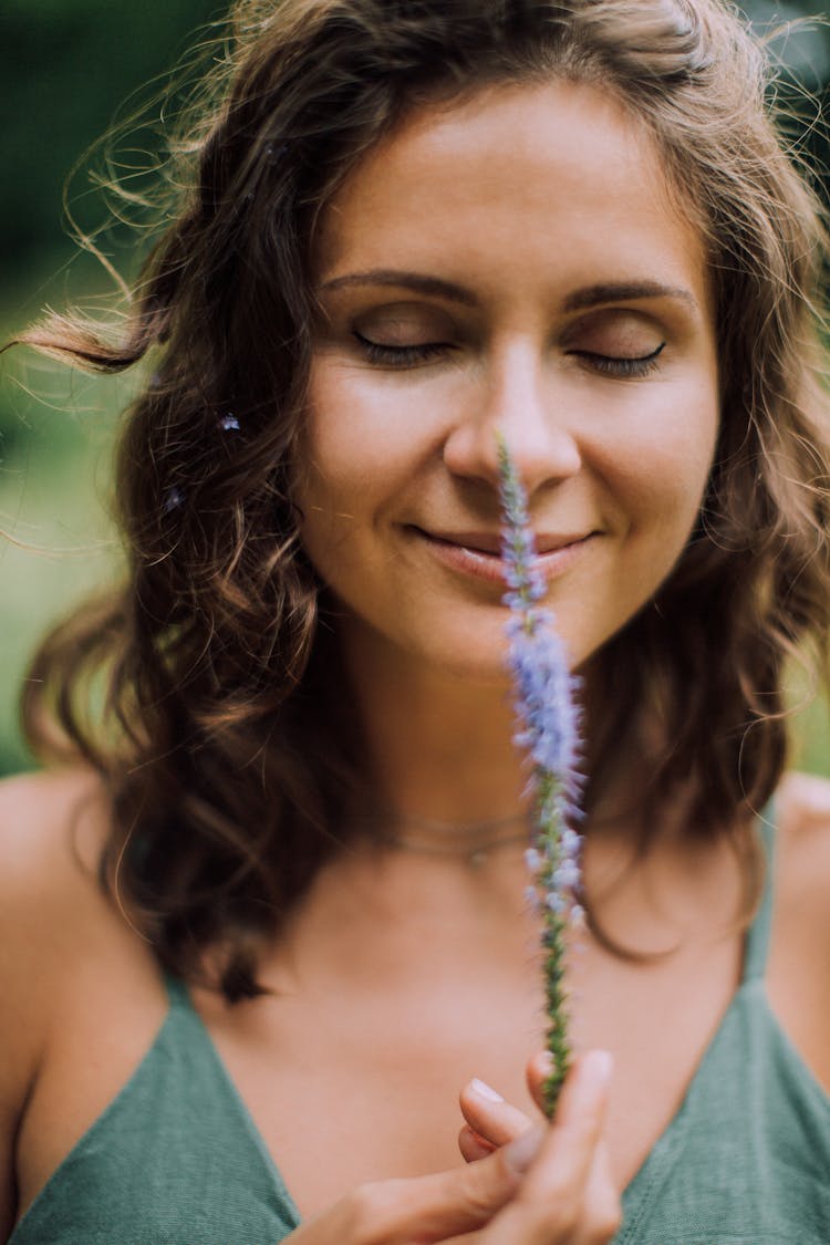 A Woman Smelling Flower While Closed Eyes