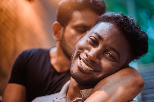 Free Close-up of a smiling LGBTQ couple embracing warmly outdoors with soft evening light. Stock Photo