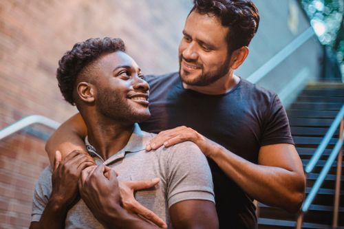 Free A joyful couple shares a warm embrace on city stairs, showcasing love and togetherness. Stock Photo