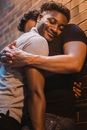 Man in Black Tank Top Hugging Woman in Gray Sweater