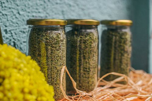 Free Close-up of glass jars filled with dried herbs against a textured wall. Stock Photo