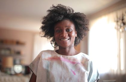Portrait of a smiling woman with natural afro hair in a cozy indoor setting — photo by Andrea Piacquadio on Pexels