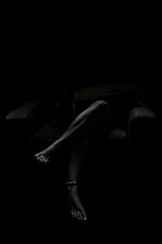 A serene black and white silhouette of a woman lounging on an armchair, exuding tranquility and mystery.