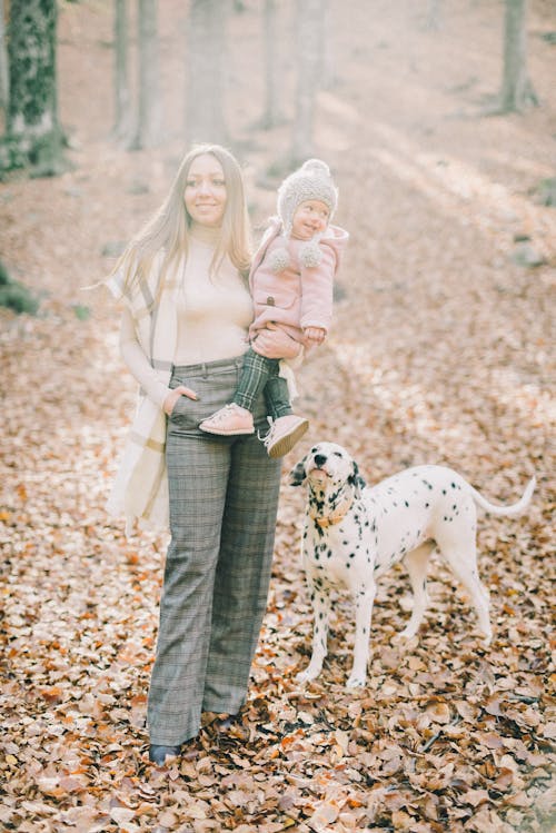 A Woman Carrying her Daughter in the Woods with a Dog