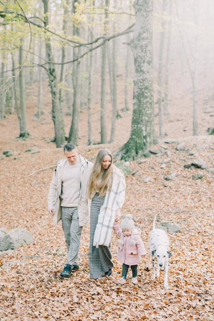 A Happy Family Walking In The Woods With Their Dog